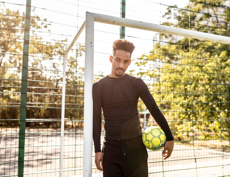 Foto gratuito uomo afroamericano in posa con un pallone da calcio