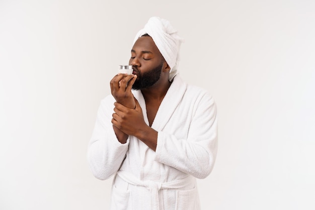 Uomo afroamericano sorridente che applica crema sul viso Concetto di cura della pelle dell'uomo