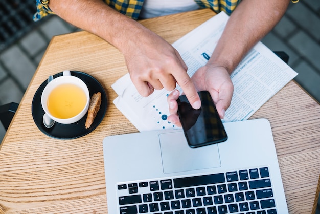 Uomo al tavolo con caffè e gadget