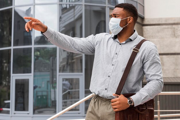 Uomo all'aperto che punta a qualcosa mentre si reca al lavoro durante una pandemia