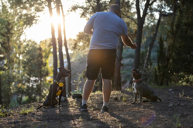 Uomo all'aperto in una sessione di addestramento del cane con due cani