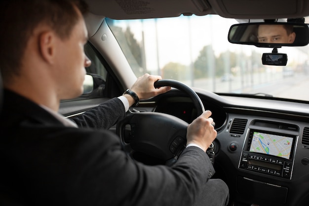 Uomo alla guida della sua auto elegante per i servizi di taxi