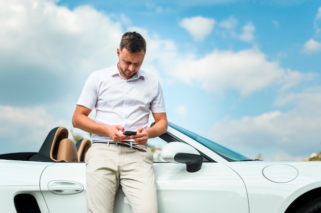 Uomo alla moda che esamina vista frontale del telefono