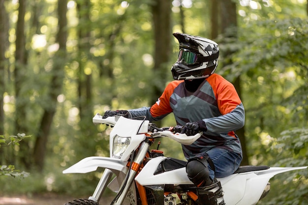 Uomo alla moda che guida una motocicletta nella foresta