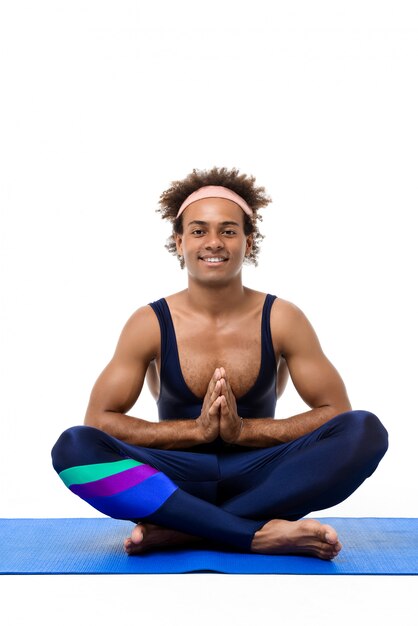Uomo allegro che meditating, seduto sul tappetino yoga