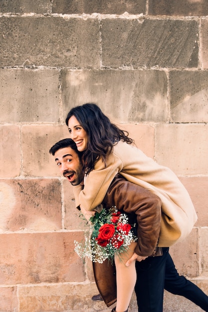 Uomo allegro che porta la donna sulla schiena