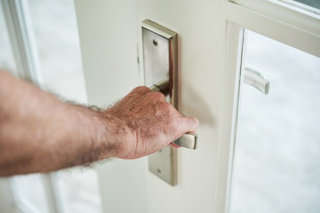 Uomo anonimo ritagliato che tiene la maniglia della porta per aprire la porta