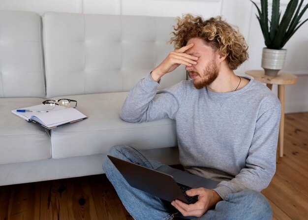 Uomo ansioso che tiene vista laterale del laptop