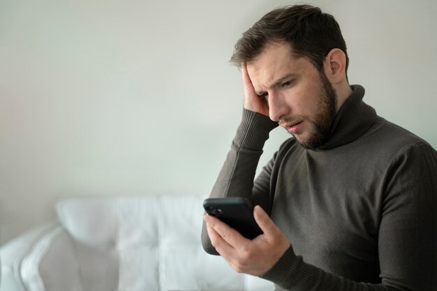 Uomo ansioso di vista laterale che tiene smartphone