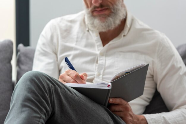 Uomo anziano a casa che studia e prende appunti