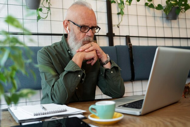 Uomo anziano a tiro medio che studia con il computer portatile