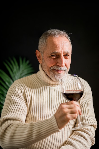 Uomo anziano allegro con bicchiere di vino