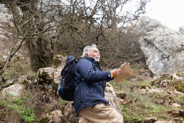 Uomo anziano che fa un'escursione con il colpo medio della mappa