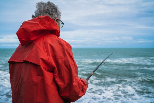 Uomo anziano che pesca nel mare.
