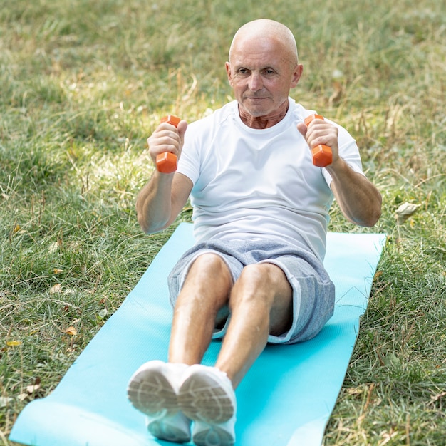 Uomo anziano che risolve sulla stuoia di yoga