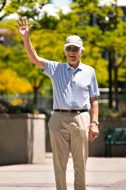 Uomo anziano che saluta mentre fa una passeggiata all'aperto