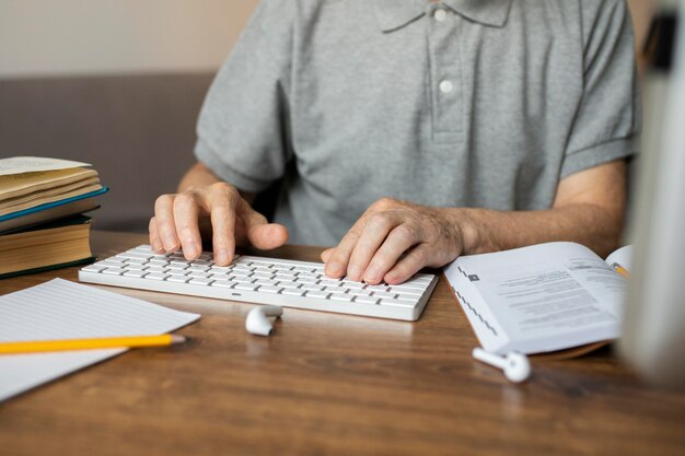 Uomo anziano che segue una lezione online sul suo computer