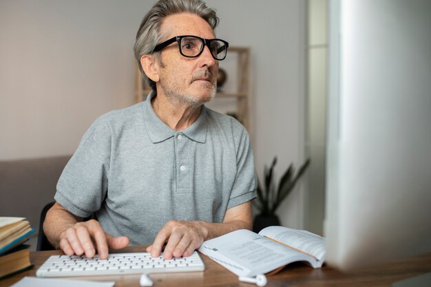 Uomo anziano che segue una lezione online sul suo computer