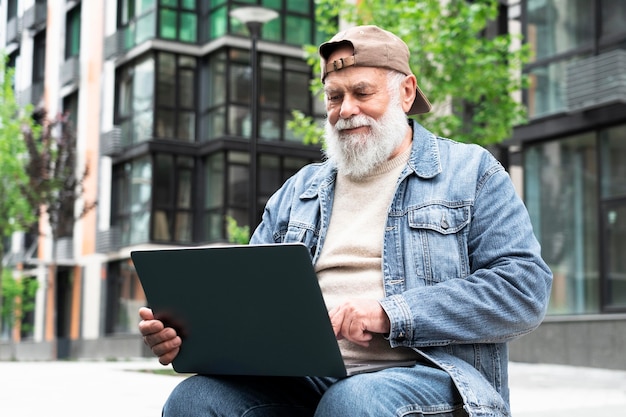 Uomo anziano che utilizza laptop all'aperto in città