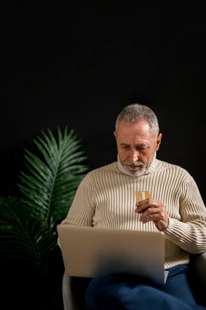 Uomo anziano con carta di credito usando il portatile