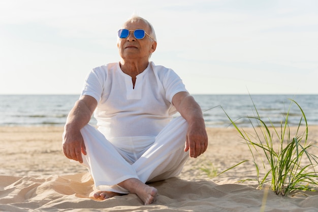Uomo anziano con occhiali da sole che riposa sulla spiaggia