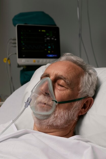 Uomo anziano con respiratore in un letto d'ospedale
