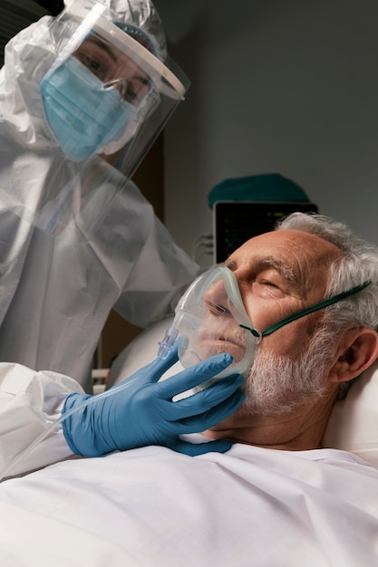 Uomo anziano con respiratore in un letto d'ospedale