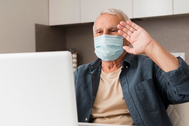 Uomo anziano del colpo medio che fluttua al laptop