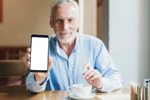 Uomo anziano del colpo medio che tiene uno smartphone