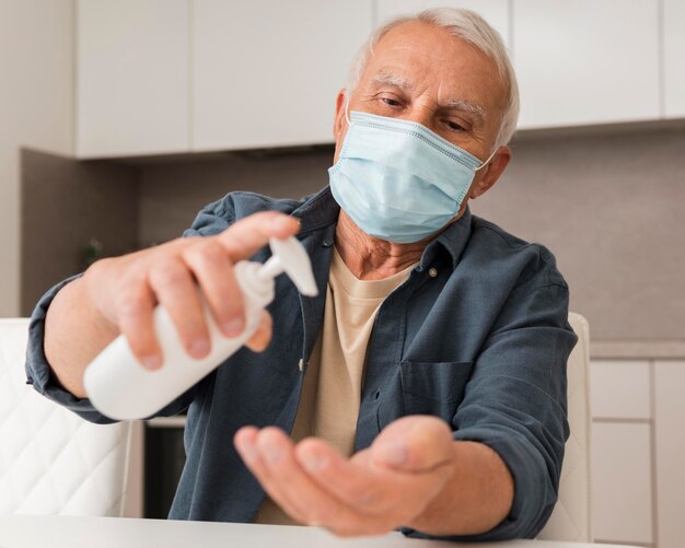 Uomo anziano del colpo medio che versa disinfettante