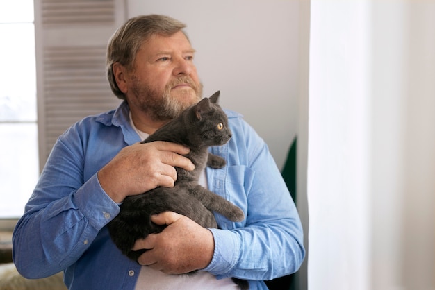 Uomo anziano del colpo medio con il gatto