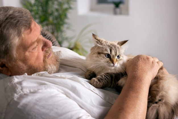 Uomo anziano del colpo medio con il gatto