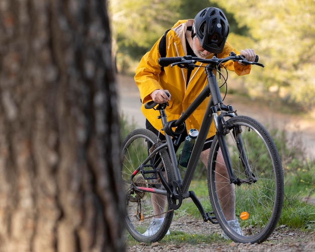 Uomo anziano del ritratto con la bici sulla montagna