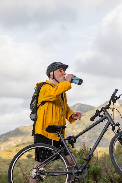 Uomo anziano del ritratto con la bici sulla montagna