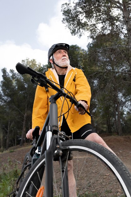 Uomo anziano del ritratto con la bici sulla montagna