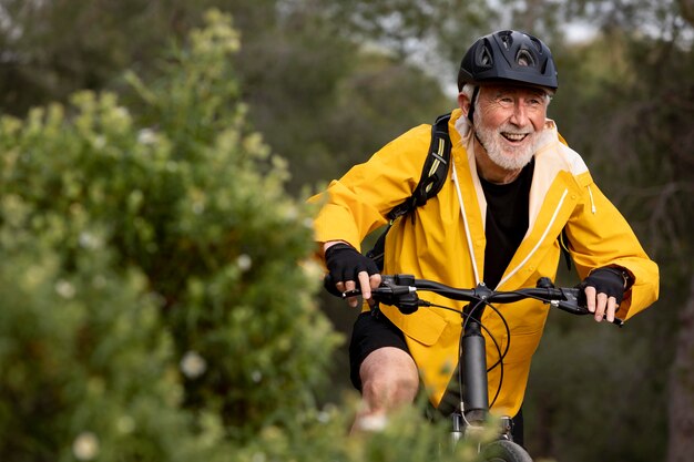 Uomo anziano del ritratto con la bici sulla montagna