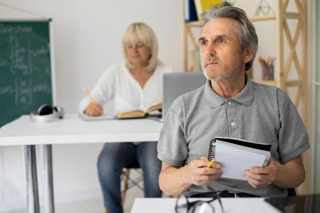 Uomo anziano e donna che prestano attenzione in classe