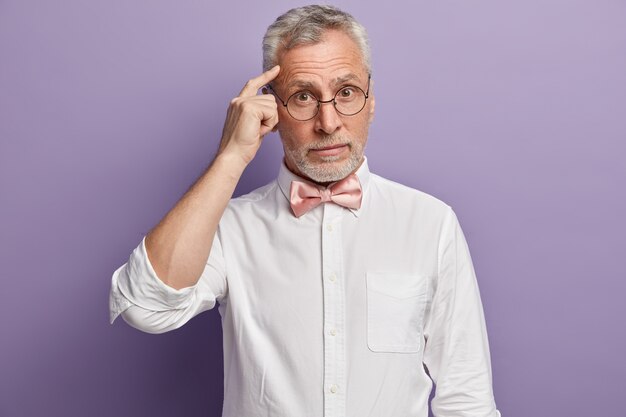 Uomo anziano in camicia bianca e papillon rosa