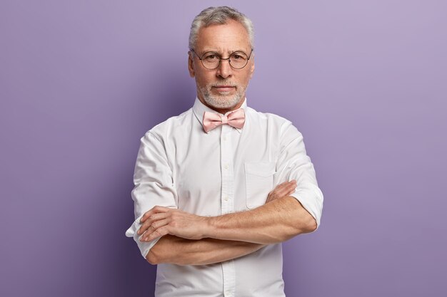 Uomo anziano in camicia bianca e papillon rosa