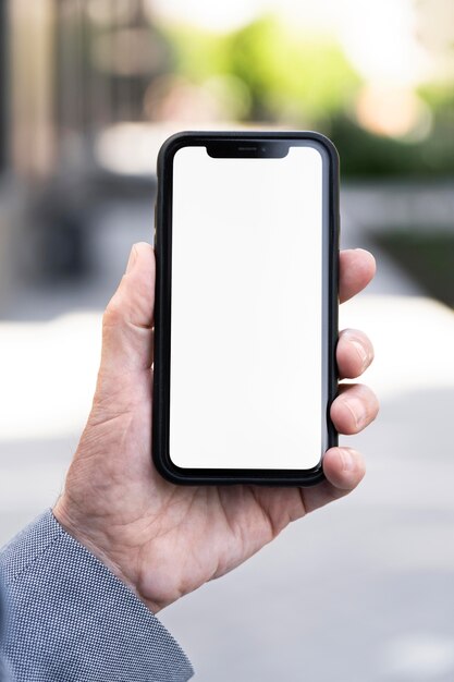 Uomo anziano in città con in mano uno smartphone