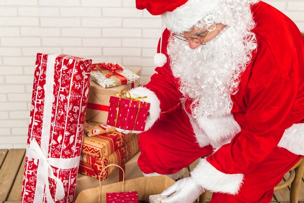 Uomo anziano in costume di Babbo Natale che mette i regali nella borsa di Kraft