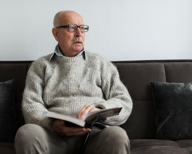 Uomo anziano in una casa di cura che legge un libro