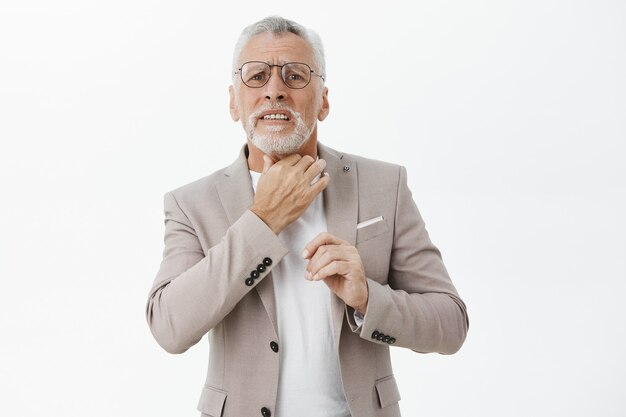 Uomo anziano preoccupato che si tocca il collo, lamentando mal di gola