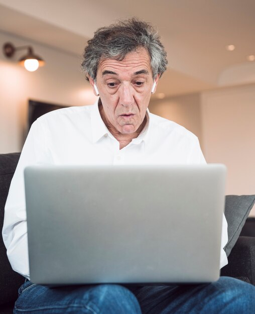 Uomo anziano scioccato guardando portatile