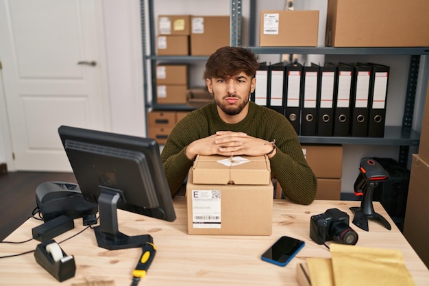 Uomo arabo con la barba che lavora presso un e-commerce di piccole imprese scettico e nervoso accigliato sconvolto a causa del problema della persona negativa