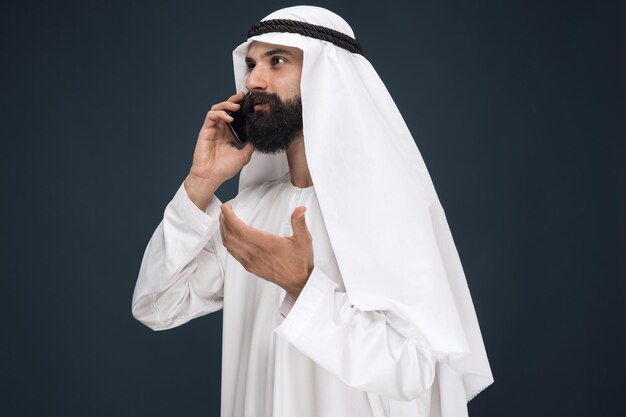 Uomo arabo saudita su sfondo blu scuro per studio