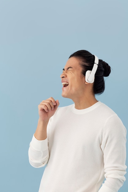Uomo asiatico bello che ascolta la musica tramite le cuffie