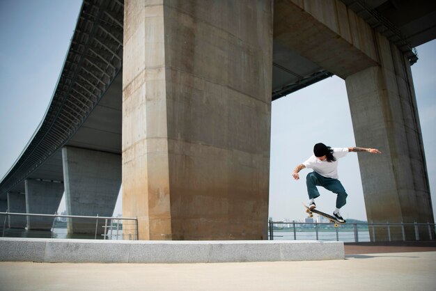 Uomo asiatico che fa skateboard in città all'aperto