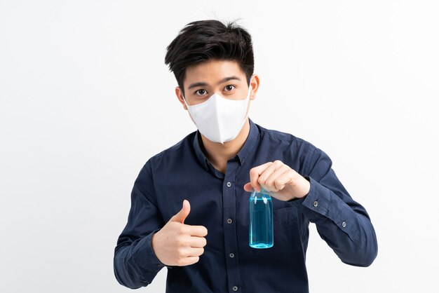 Uomo asiatico che indossa una maschera per il viso in possesso di alcol per lavarsi le mani per proteggere il Coronavirus covid-19 nella stanza di quarantena