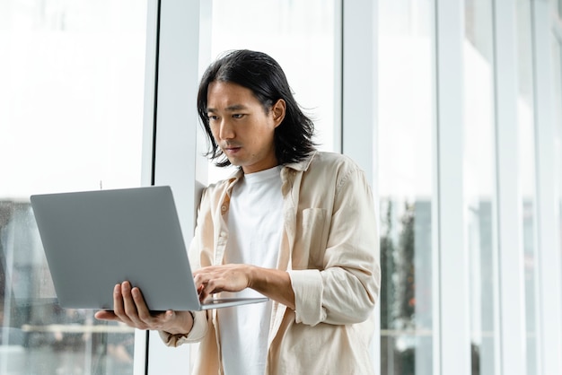 Uomo asiatico che usa il laptop mentre è in giro per la città